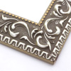 A large, reverse curve profile frame with an intricate leaf design bordered by a geometric outer edge and beaded inner lip.  A matte grey base, with silver foil patina along the topmost points of the design.  The beading is gold foil. Strong, solid wood construction.

2.75 " width: ideal for large and extra large (oversize) images.